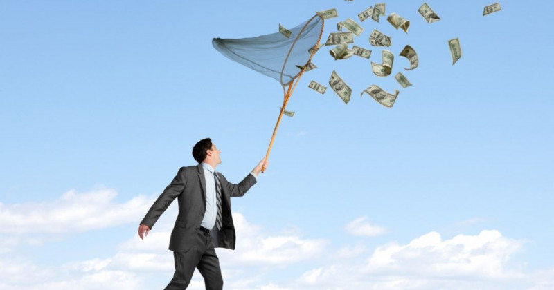 Empresario a la caza de billetes con una red para mariposas