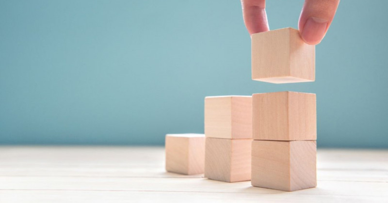 Una mano coloca cubos de madera sobre una mesa