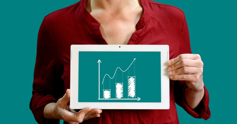 Una mujer muestra una tableta con un gráfico ascendente